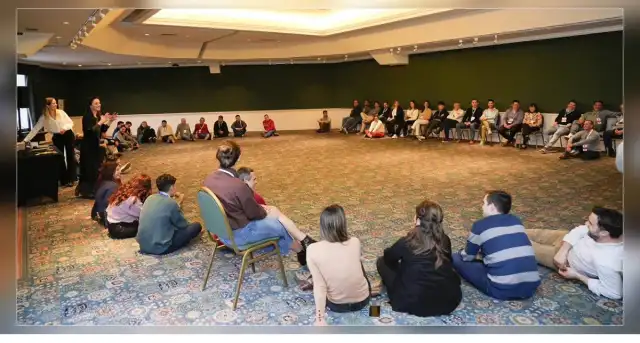 Participantes sentados en una gran ronda en una sala de encuentros.